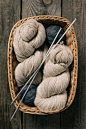 Top view of beige and grey knitting yarn wit knitting needles in wicker basket on wooden background #lifestyle #photography #knitting #yarn #hobby #cozy #handmade #crafting