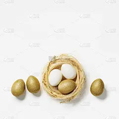复活节金蛋在稻草巢在白色的背景。流行的春节金蛋。顶视图闪耀复活节最小的创意组成。复活节春假快乐