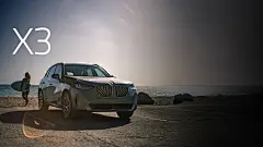 The BMW X3 30 xDrive parked on a beachfront with a surfer walking away from it toward the ocean.
