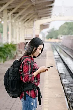 年轻美丽的女性旅行摄影师喜欢在她的旅程在火车站拍照。亚洲妇女旅行与相机有乐趣的照片，而等待火车。