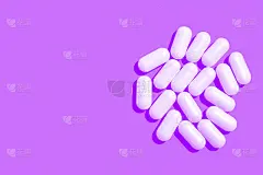 紫色背景上的白色药片胶囊。副本的空间。