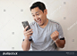 Portrait of happy funny Asian man shocked or surprised with mouth open, good news on smart phone concept, amazed winning gesture