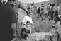  2002，男孩抓住父亲的裤子，蹲坐在他父亲即将下葬的墓地旁边，周围是为亚美尼亚地震死难者挖掘坟墓的士兵和村民。