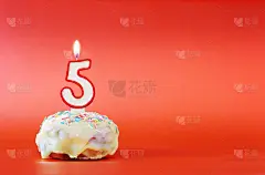 五年的生日。纸杯蛋糕，上面有燃烧着的白色蜡烛，形状是5号。鲜艳的红色背景与复制空间