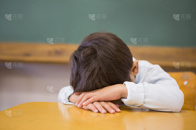 困倦的小学生在教室的课桌上打盹