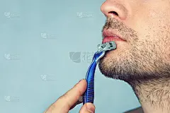 一名男子在不使用泡沫、肥皂和剃须膏的情况下剃须。刮干。广告海报，有文字空间。副本的空间。
