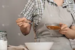 家庭主妇手中的一个玻璃碗，上面放着棕色的椰糖。用低血糖指数的糖制作烘焙食品的概念，是为糖尿病患者准备