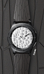 The Gear S3 ‘Facet’ model is laid out on a background that is a close-up of its black patterned band.