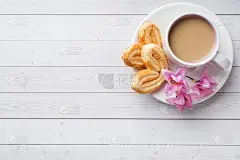 情人节早餐概念。白色桌子上放着一杯咖啡和一块爱心饼干。复制空间，平铺。