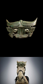 瑞士私人收藏西周早期：青铜兽面马冠。宽23厘米。采用了西周早期流行的牛角兽面。牛角与耳之间，以及咬合的兽牙中间刚好制成了穿绳的孔，用于固定在马额头。