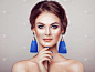 美丽的女人带着大耳环和宝石蓝色.完美的化妆和优雅的发型。蓝色化装箭