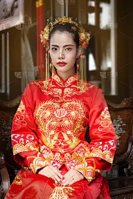 亚洲妇女穿着红色的传统中国服装坐在木凳上，看中国歌剧。