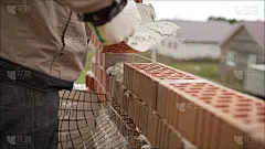 工人筑起一堵砖墙。在砖墙施工现场工作的砌砖工。砖匠正在工地上放另一排砖