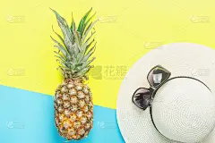 成熟的菠萝女人的草帽太阳镜在分裂的双色调黄蓝色背景。夏季度假旅游热带水果时尚概念。平铺安排与复制空间