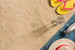 暑假的作文。人字拖，水瓶和草帽上的沙子背景。强光和阴影。夏天的背景。由毛巾制成的边饰