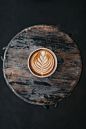 Coffee latte art viewed from above in a cup on the wooden table at Two Guns Espresso