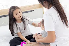 年轻的亚洲母亲和女儿坐在床上和小女婴一起玩耍，妈妈和孩子们放松，家人的情感和幸福的表达，父母和新生儿