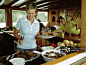 Woman standing over food in galley of boat, friends in background_创意图片