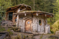 This may contain: a small house made out of rocks in the middle of a forest with trees around it