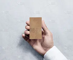 手持空白垂直牛皮纸名片设计模型。