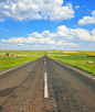 Free Gray Asphalt Road Between Green Grass Field Under Blue and White Sunny Cloudy Sky Stock Photo