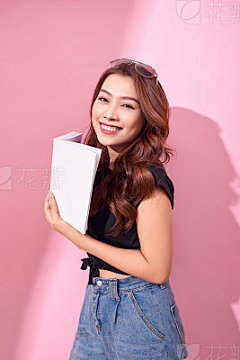Lovely girl wearing summer clothes standing isolated over pink background, holding a bookLovely girl wearing summer clothes standing isolated over pink background, holding a book