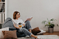 Fulllength shot of young woman in stylish outfit girl enjoys book and coffee while sitting in cozy room