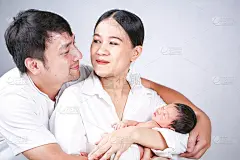 父母带着孩子。一个年轻的家庭和小儿子的肖像。快乐的年轻爸爸选择性地亲吻妈妈和拥抱婴儿宝宝。