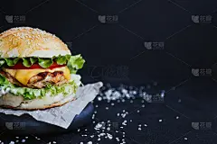 美味的自制汉堡，配上鸡排，生菜，番茄，芝士和酱汁。在黑色背景的木板上