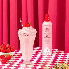 a table topped with a milkshake and a bowl of strawberries
