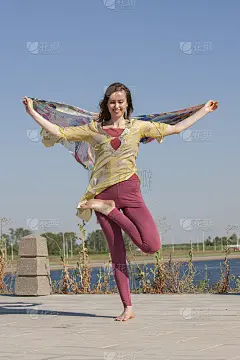 女人在河边做瑜伽，享受大自然的好天气和正能量。