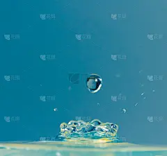 水滴落在蓝色的背景上溅起水花。宏观性质的照片