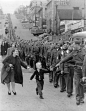 “Wait For Me Daddy,” October 1, 1940: A line of soldiers march in British Columbia on their way to a waiting train as five-year-old Whitey Bernard tugs away from his mother’s hand to reach out for his father.