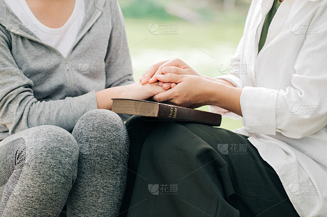 两名妇女手牵过圣经祈祷崇拜信仰。