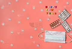 白色的雪花，药丸和医用口罩，红色背景上的题字新年快乐。寒假与生病