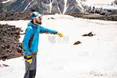一个戴着眼镜戴着冰锥的登山者站在雪山的背景上
