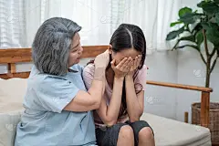 亚洲慈爱的老年母亲安慰和安慰沮丧沮丧的年轻女孩的女儿哭泣的问题。关心老妈妈的支持和理解，同情在家里流