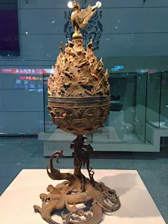 This may contain: an ornately decorated vase on display in a glass case