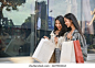Happy and beautiful young Asian woman enjoy shopping with her friend, checking her purchases in a shopping bags, walking along the mall building. Urban and shopping lifestyle concept 库存照片