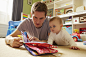 Mid adult man and baby daughter reading storybook in playroom