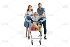 快乐的父母抱着可爱的儿子坐在堆满食品的购物车里
