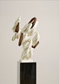 This may contain: the sculpture is made up of white and brown objects on a black pedestal with a gray wall in the background