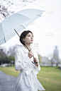 一个穿着白色连衣裙的年轻女子撑着伞在雨中行走