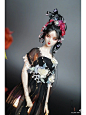 其中可能包括：a doll wearing a black dress with flowers in her hair
