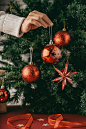 Hand of unrecognizable woman holding bauble in front of christmas tree Free Photo