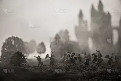 有骑兵和步兵的中世纪战斗场景。剪影的人物作为单独的对象，战斗之间的战士在日落雾蒙蒙的背景。