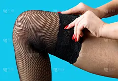 一个修了漂亮指甲的女人把长袜套在腿上。