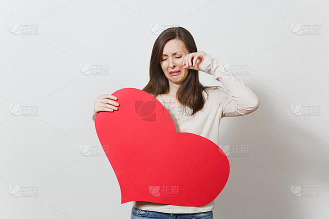 伤心难过，悲痛欲绝，哭泣哭泣的女人手里捧着一颗大大的红心，放在白色的背景上。广告版面复制。文本。情人