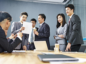 一支由亚洲企业高管组成的团队在办公室工作...