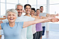 Portrait of fitness class stretching hands in row at yoga class